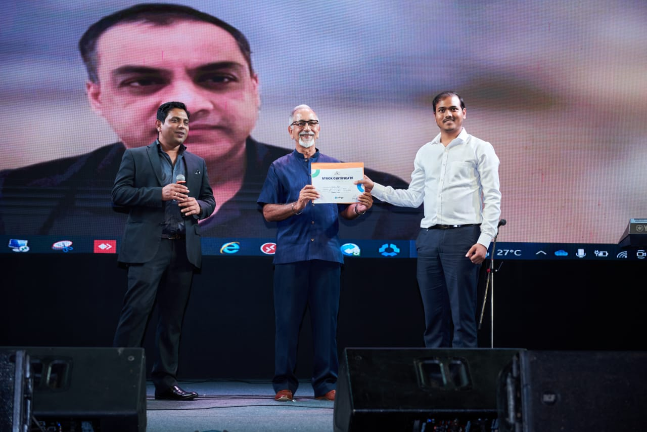 Kundan Kumar Singh receiving a stock certificate on stage